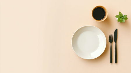 A stylish minimalist table setting featuring a white plate, black utensils, a coffee cup, and a small green plant on a soft peach surface, perfect for modern dining decor.の素材