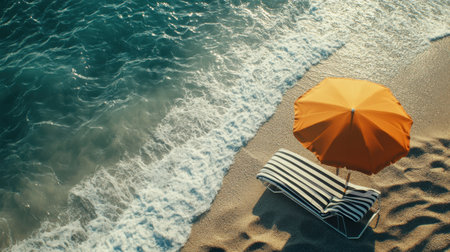 A tranquil beach setting featuring a striking orange umbrella and a lounge chair, inviting relaxation as the gentle waves touch the sandy shore, ideal for summer escapes.の素材