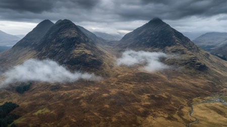 Breathtaking aerial view of the Scottish Highlands showcasing rugged mountain peaks enveloped in fog and dramatic clouds, highlighting the exquisite beauty of nature.の素材