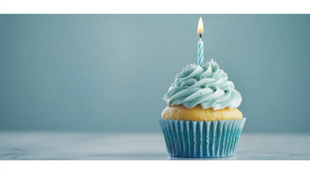 A beautifully crafted cupcake with blue frosting and a lit candle stands against a serene background, symbolizing joy and celebration in every delicious bite.の素材
