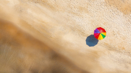 Discover a serene scene of a colorful umbrella on a sandy beach from above, showcasing the perfect summer getaway with vibrant colors and a peaceful atmosphere.の素材