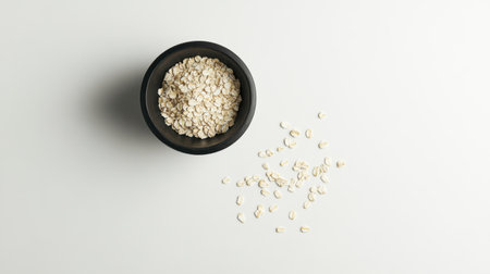 A captivating overhead shot of a bowl filled with raw oats, elegantly placed on a clean white background, showcasing the healthy and versatile ingredient ideal for various culinary uses.の素材