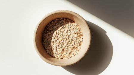 A close-up view of natural oats in a simple bowl, showcasing texture and light interplay, ideal for health-conscious cooking and minimalist food aesthetics.の素材