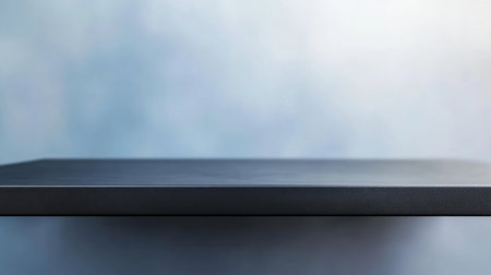This image showcases an empty black surface set against a soft blue background featuring gentle gradients, perfect for showcasing products or creating clean design elements in visual art.の素材