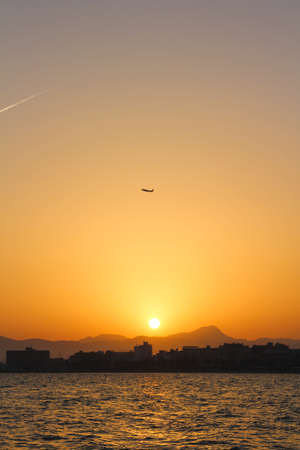 Plane flying during the sunset at the beachの写真素材