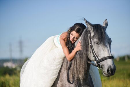 Beautiful and stunning bride,  on a horse in the nature, on her wedding dayの写真素材