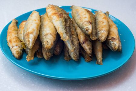 Fried fish lays on a white plate over gray tableclothの写真素材