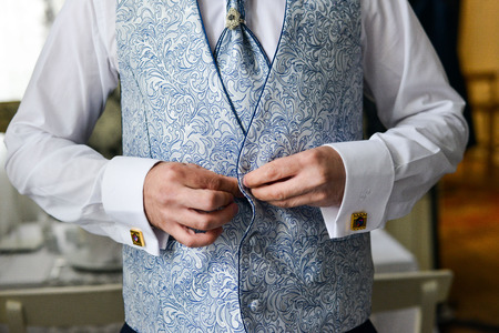 Close-up of a man in a tux fixing his cufflink. groom bow tie cufflinks