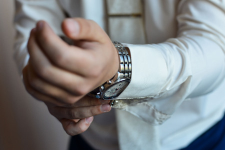 Close-up of a man in a tux fixing his cufflink. groom bow tie cufflinksの写真素材