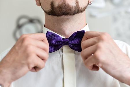 Close-up of a gentleman wearing Black Tie straightens his bowtie.の写真素材