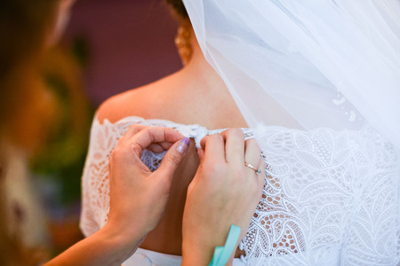Garter on the leg of a bride, slim sexy bride in wedding luxury dress showing her silk garter with golden ribbon. woman have a final preparation for wedding ceremony. Wedding day momentsの写真素材