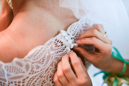 Garter on the leg of a bride, slim sexy bride in wedding luxury dress showing her silk garter with golden ribbon. woman have a final preparation for wedding ceremony. Wedding day momentsの写真素材