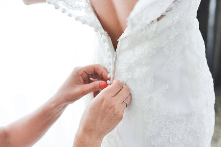 Garter on the leg of a bride, slim sexy bride in wedding luxury dress showing her silk garter with golden ribbon. woman have a final preparation for wedding ceremony. Wedding day momentsの写真素材