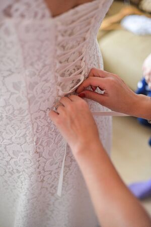 Garter on the leg of a bride, slim sexy bride in wedding luxury dress showing her silk garter with golden ribbon. woman have a final preparation for wedding ceremony. Wedding day momentsの写真素材