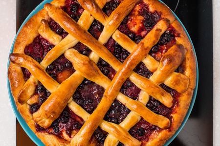 Cherry pie with lattice top on fall themed napkin, and mini pumpkins.の写真素材