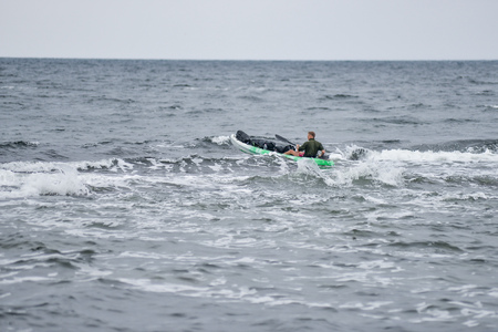 Kayak surfer over the crest of a wave in rough seaの写真素材