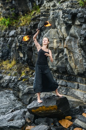 Girl in a black suit with flaming torches. fire