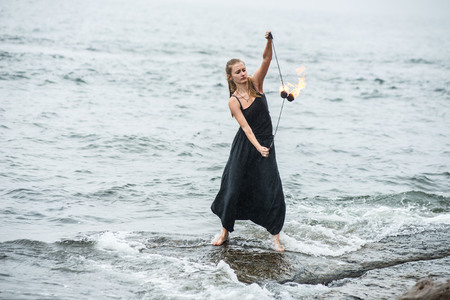 Girl in a black suit with flaming torches. fireの写真素材
