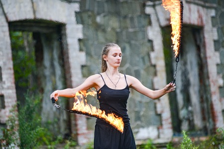 Girl in a black suit with flaming torches. fire