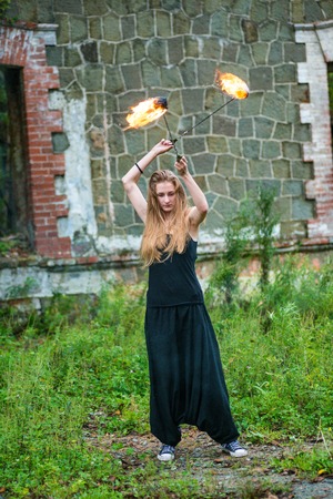 Girl in a black suit with flaming torches. fireの写真素材