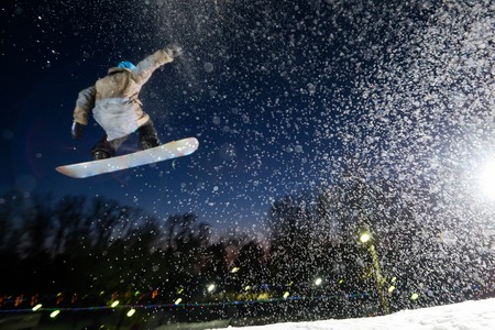 Snowboarder jumping at nightの写真素材