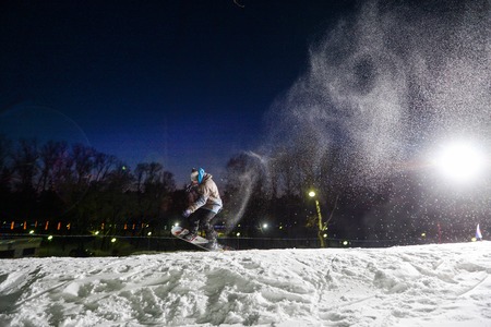 Snowboarder jumping at night