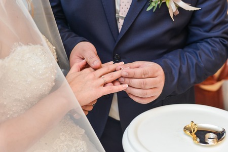 marriage hands with rings. birde wears the ring on the finger of the groomの写真素材