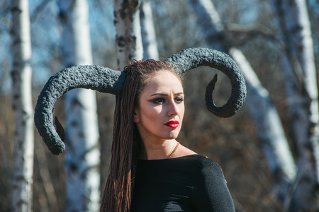 beautiful woman dressed as a fairy witch in raincoat and with horns for Halloweenの写真素材