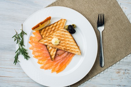 Smoked salmon with fresh dill on bread slice, in natural light, authentic food. red salted fish with breadの写真素材