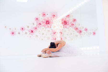 Young and incredibly beautiful ballerina is posing and dancing in a white studio full of light.の写真素材