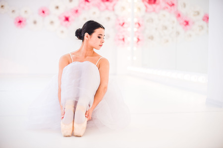 Young and incredibly beautiful ballerina is posing and dancing in a white studio full of light.の写真素材