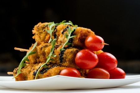 vegetables on skewer fried in batter decorated with tomatoes zucchini, eggplant, zucchini. white plate on white backgroundの写真素材