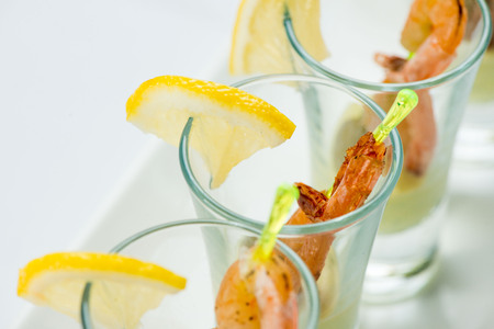 individual Cocktail Shrimp shot glasses with delicious homemade tartar spicy sauce decorated with parsley leaf for Christmas dinner or cocktail party, bokeh background, close-upの写真素材