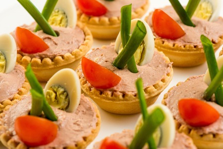 Three baguette slices with liver and apple pate and a thin tomato slice on top. Shallow DOFの写真素材