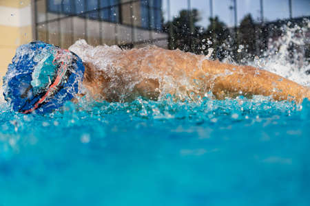 Man swims using breaststroke technique . pool turquoise waterの写真素材
