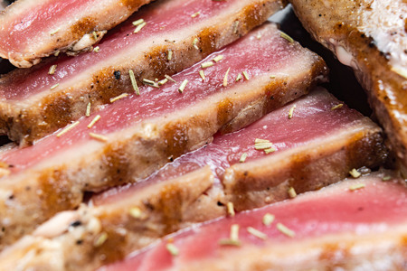 Close Up Still Life of Roasted Tuna Steaks Crusted with Herbs and Sesame Seeds on Dark Gray Surfaceの写真素材