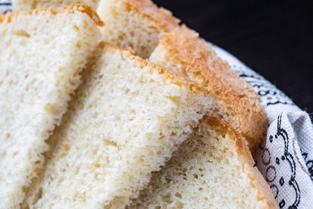 Fresh homemade baked bread and sliced bread on rustic white wooden table