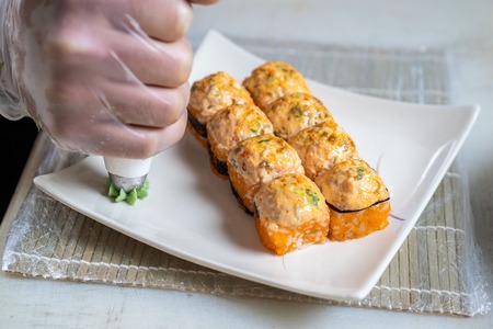 Cook hands making japanese sushi roll. Japanese chef at work preparing delicious sushi roll with eel...