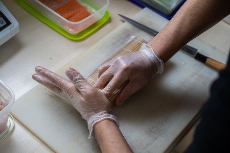 Cook hands making japanese sushi roll. Japanese chef at work preparing delicious sushi roll with eel and avocado. Appetizing japanese food.の写真素材