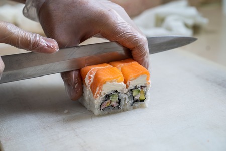Cook hands making japanese sushi roll. Japanese chef at work preparing delicious sushi roll with eel and avocado. Appetizing japanese food.の写真素材