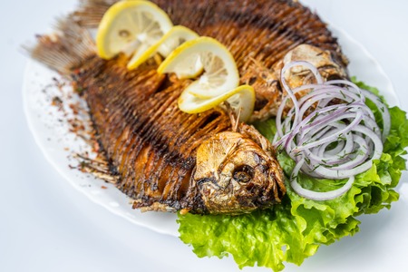 Grilled carp fish on the white plate over white