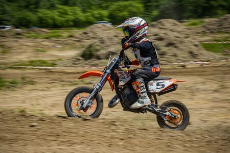 KHABAROVSK, RUSSIA - june 16, 2019 :Racer child on motorcycle participates in motocross cross-country in flight, jumps and takes off on springboard against sky. Concept active extreme rest teenager.のeditorial素材