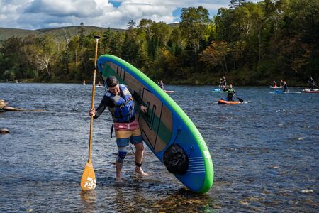 KHABAROVSK, RUSSIA - September 20, 2019 : Water tourists paddle SUP Stand up paddle board on the mountain river Anyui against the backdrop of beautiful mountains and wildlifeのeditorial素材