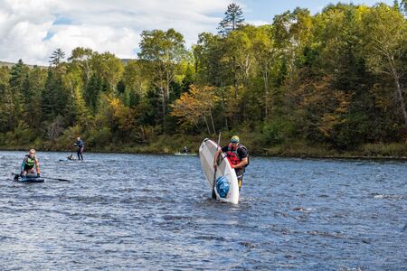 KHABAROVSK, RUSSIA - September 20, 2019 : Water tourists paddle SUP Stand up paddle board on the mountain river Anyui against the backdrop of beautiful mountains and wildlifeのeditorial素材