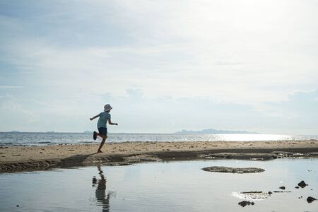 Silhouette, a child walking with reflection on water.の写真素材