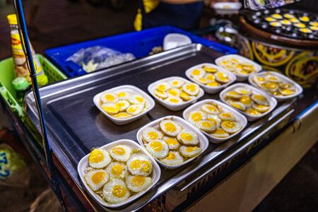 Traditional Thai Street Fast Food, quail eggs cooked in heating mantle hot indented frying pan. Asian Cuisine, Delicacy, Culture, Cooking, Snack Food, Indulgence, Nutrition and Gourmet concept.の写真素材