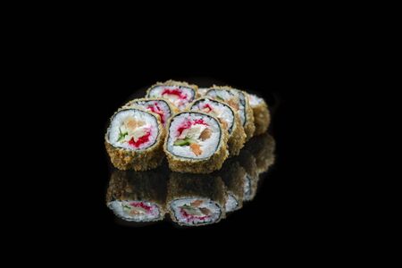 A close up of food fried sushi rolls isolated on black. reflection