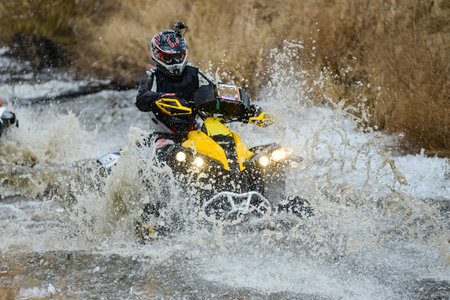 The man on the ATV crosses a stream. Tourist walks on a cross-country terrain.の写真素材