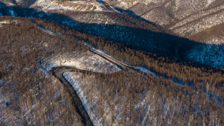 Aerial view of the river and taiga forests and road in the winter - springtime . Abstract landscape of northern nature with drone.の写真素材