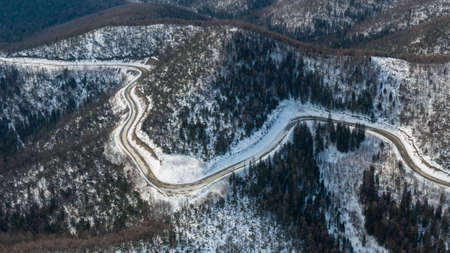 Aerial view of the river and taiga forests and road in the winter - springtime . Abstract landscape of northern nature with drone.の写真素材